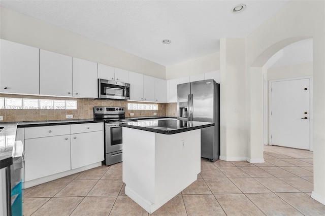 kitchen featuring white cabinetry, light tile patterned floors, tasteful backsplash, and appliances with stainless steel finishes