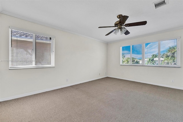 empty room featuring visible vents, ornamental molding, carpet floors, baseboards, and ceiling fan