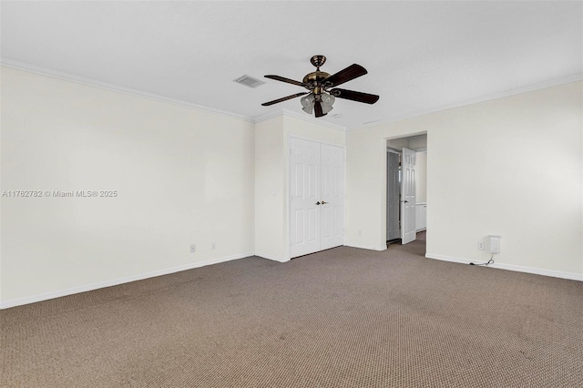 spare room featuring visible vents, a ceiling fan, crown molding, dark colored carpet, and baseboards