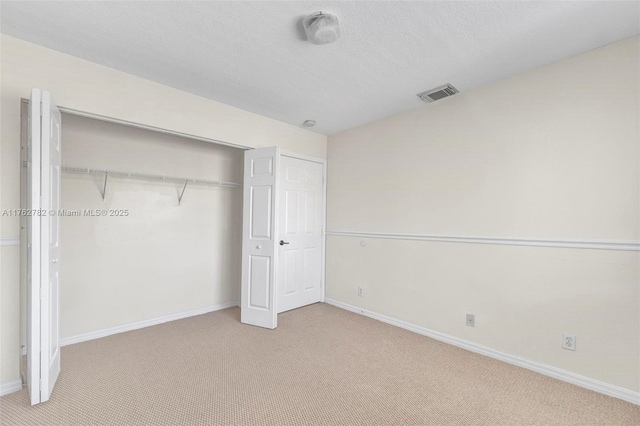 unfurnished bedroom featuring visible vents, baseboards, carpet, and a closet