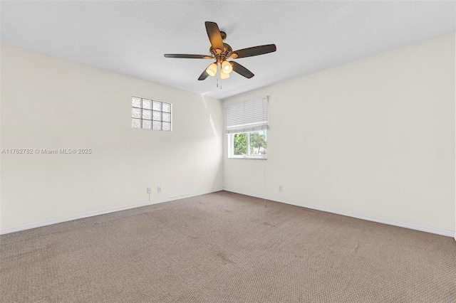 carpeted empty room featuring a ceiling fan and baseboards