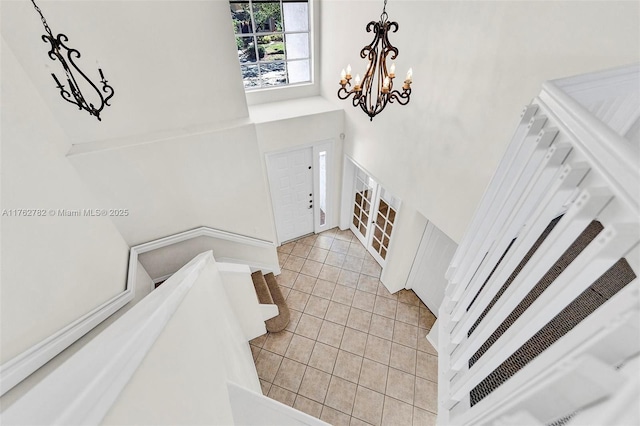 foyer featuring a notable chandelier, stairway, light tile patterned floors, and a high ceiling