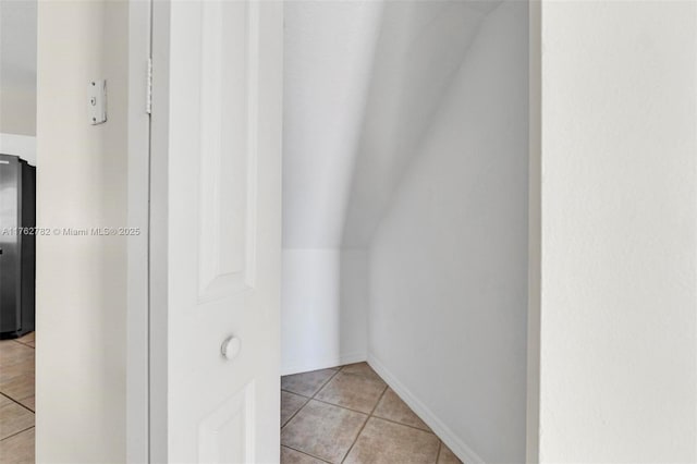 hallway with light tile patterned floors and lofted ceiling