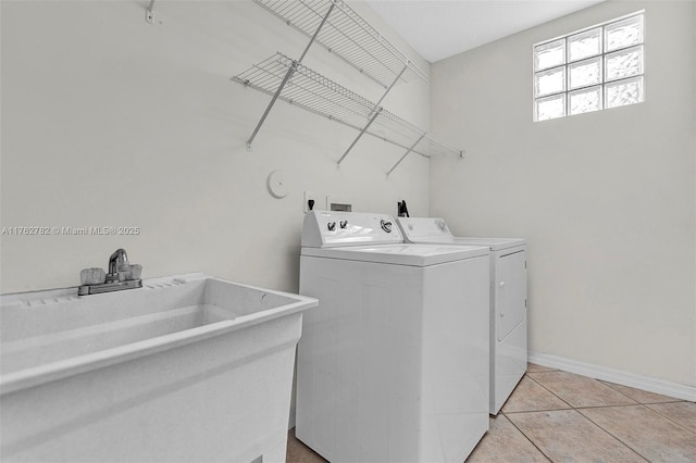 laundry area featuring baseboards, laundry area, light tile patterned flooring, a sink, and washer and clothes dryer