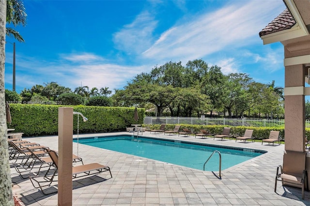 community pool with a patio area and fence