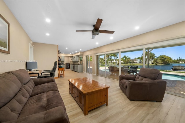 living area featuring a ceiling fan, recessed lighting, a water view, and light wood finished floors