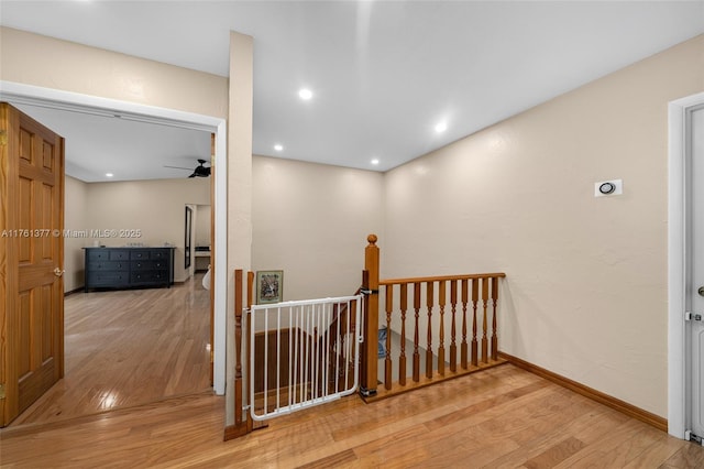 corridor with recessed lighting, baseboards, an upstairs landing, and wood finished floors