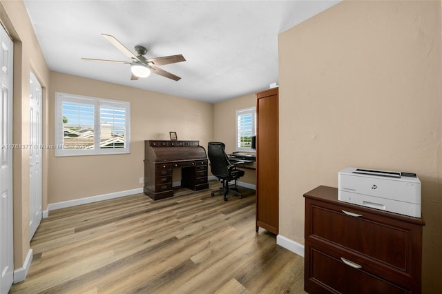 home office featuring baseboards, a ceiling fan, and light wood finished floors