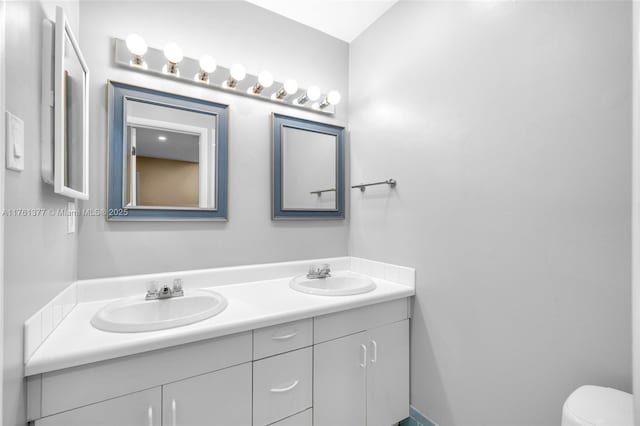 bathroom featuring double vanity, toilet, and a sink