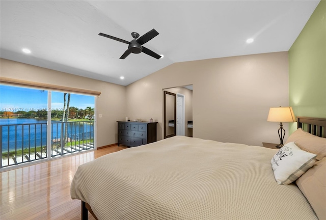 bedroom featuring a water view, wood finished floors, vaulted ceiling, and access to outside