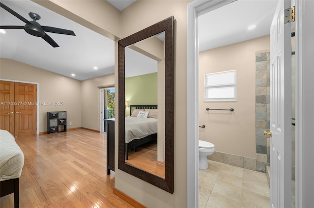 bedroom with light wood-type flooring, connected bathroom, baseboards, ceiling fan, and vaulted ceiling