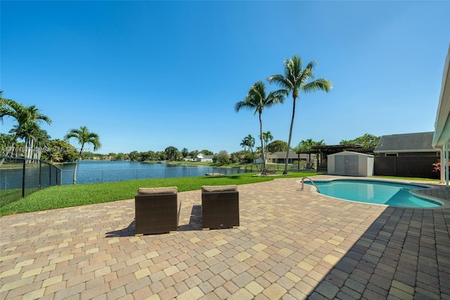 view of pool with a water view, a storage shed, an outdoor structure, and a patio area