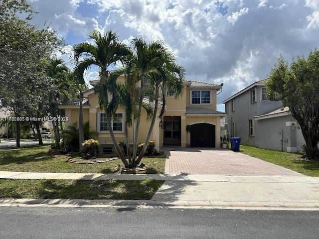 mediterranean / spanish home with a tiled roof, decorative driveway, an attached garage, and stucco siding