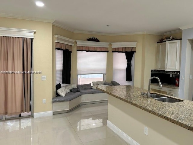 kitchen with light tile patterned floors, ornamental molding, light stone countertops, and a sink