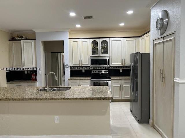 kitchen featuring a sink, light stone counters, backsplash, appliances with stainless steel finishes, and crown molding