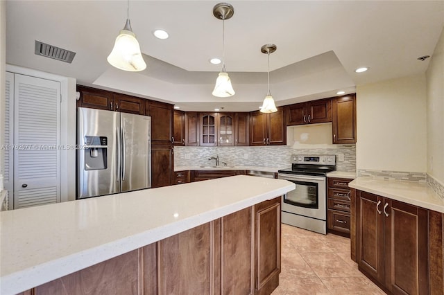 kitchen with visible vents, a sink, a tray ceiling, stainless steel appliances, and decorative backsplash