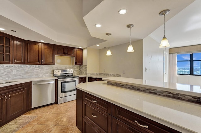 kitchen featuring pendant lighting, light countertops, light tile patterned floors, decorative backsplash, and appliances with stainless steel finishes