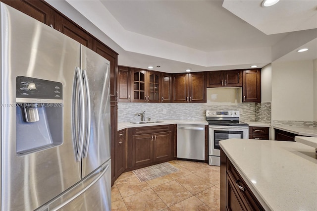 kitchen with tasteful backsplash, appliances with stainless steel finishes, light countertops, and a sink