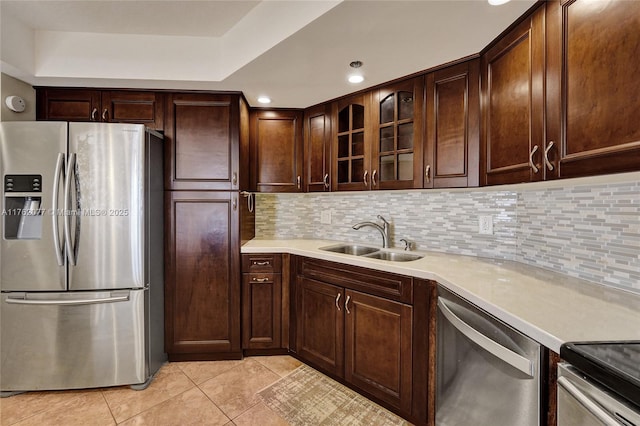 kitchen featuring a sink, stainless steel appliances, backsplash, and light countertops