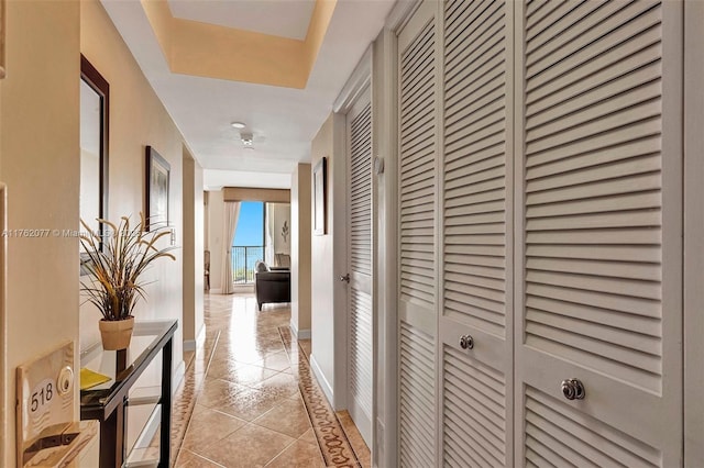 corridor featuring baseboards and light tile patterned flooring