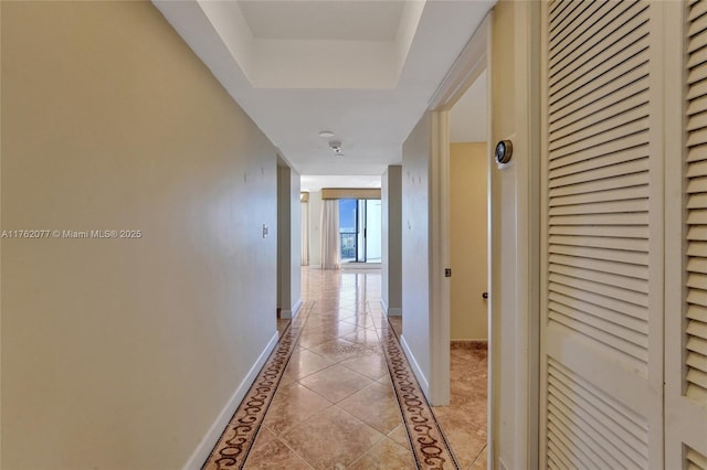 hall featuring light tile patterned floors and baseboards