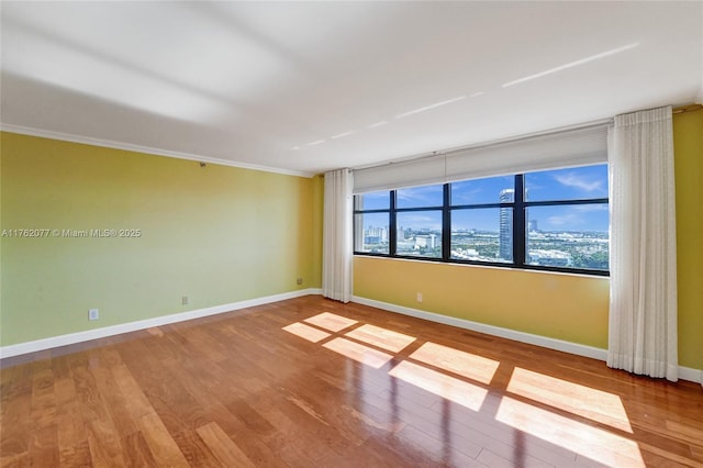 spare room with a wealth of natural light, baseboards, wood finished floors, and a view of city