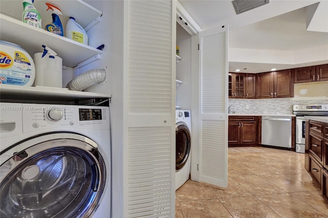 clothes washing area featuring visible vents, washer / dryer, light tile patterned flooring, and laundry area