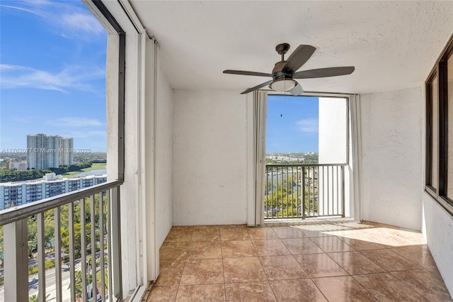 unfurnished sunroom featuring a view of city and ceiling fan