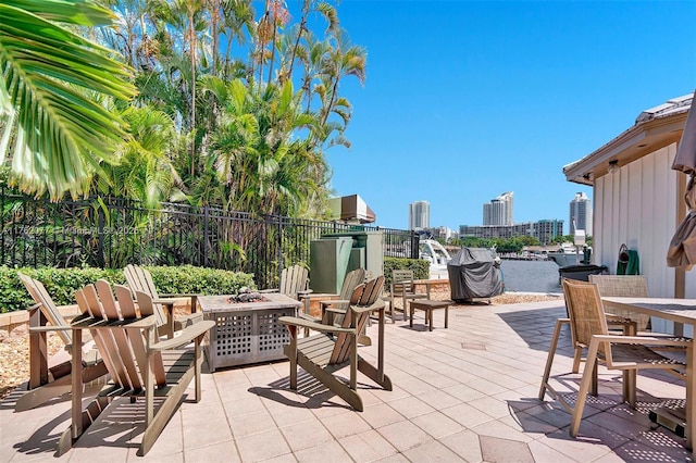 view of patio / terrace featuring a view of city, outdoor dining area, and a fire pit