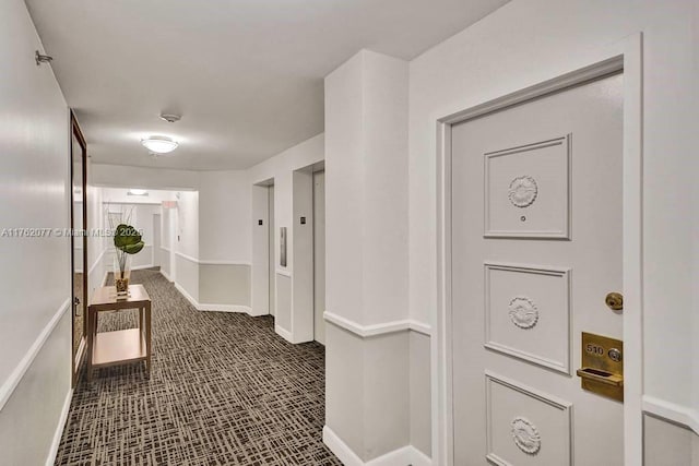 hallway featuring elevator and baseboards