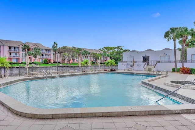 pool with a patio area, a residential view, and fence