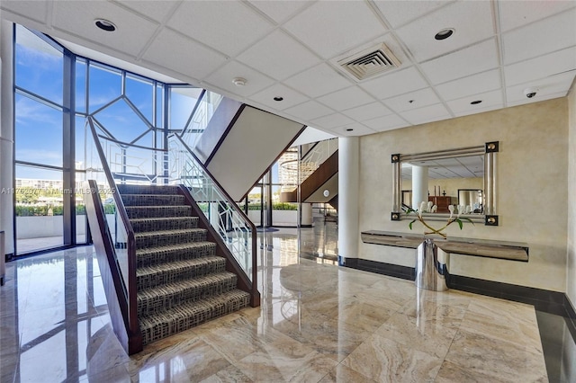 300 Three Islands Blvd Unit 518, Hallandale Beach, FL 33009 - staircase with marble tiled flooring, plenty of natural light, a drop ceiling, and expansive windows