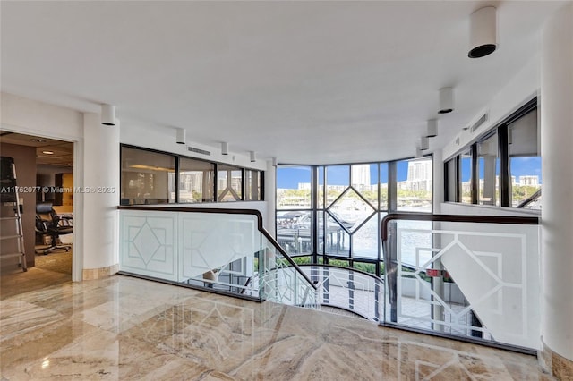 interior space featuring baseboards, marble finish floor, and floor to ceiling windows