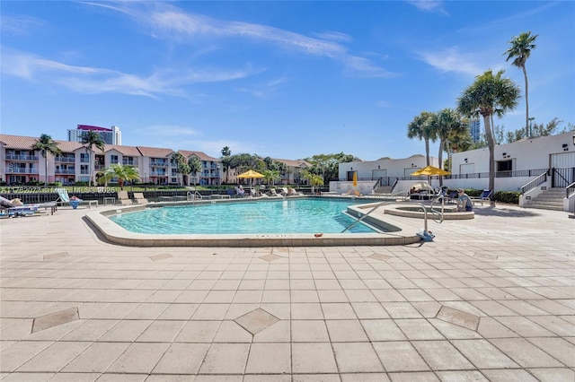 community pool with a residential view, a jacuzzi, a patio, and fence