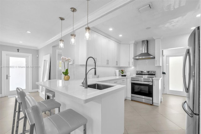 kitchen with visible vents, a peninsula, a sink, stainless steel appliances, and wall chimney exhaust hood