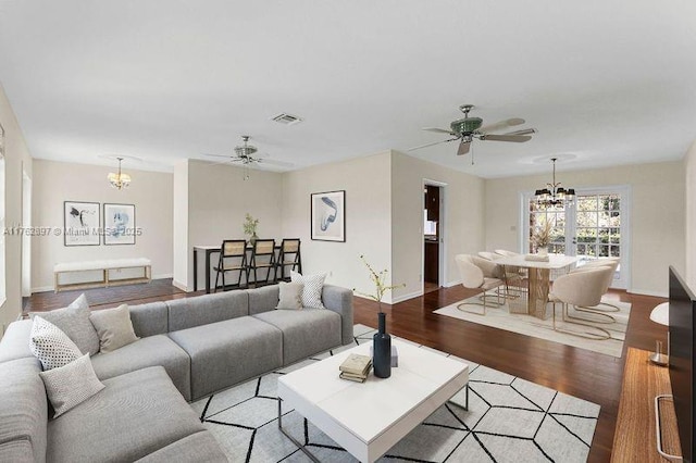 living area featuring visible vents, ceiling fan with notable chandelier, baseboards, and light wood finished floors