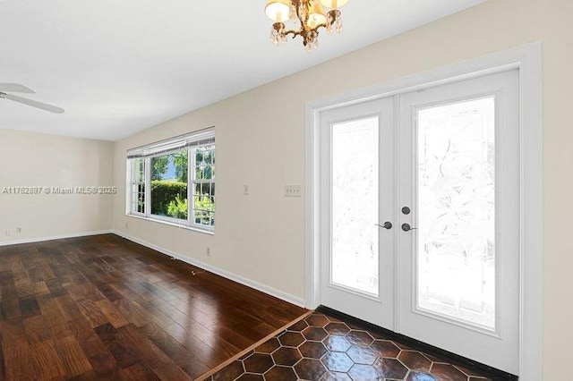 doorway with dark wood finished floors, ceiling fan with notable chandelier, french doors, and baseboards