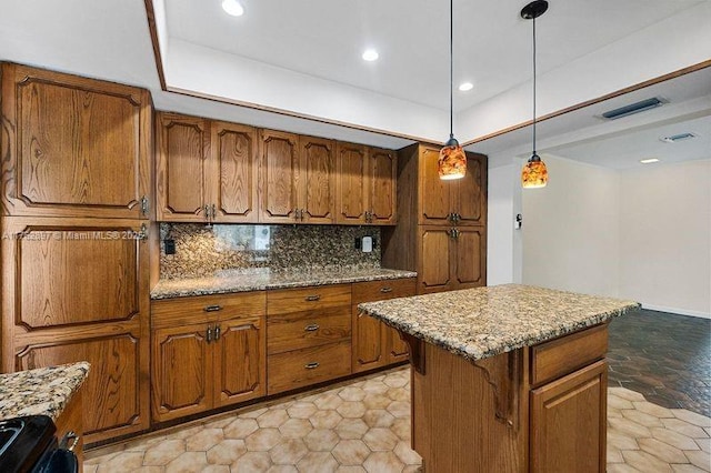 kitchen featuring backsplash, a center island, light stone countertops, decorative light fixtures, and brown cabinetry