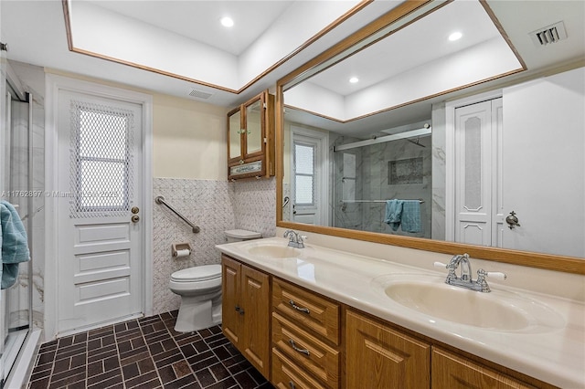 bathroom featuring visible vents, a wainscoted wall, a stall shower, tile walls, and a sink