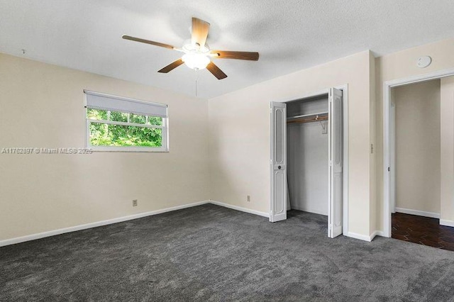 unfurnished bedroom featuring a ceiling fan, a textured ceiling, a closet, dark colored carpet, and baseboards