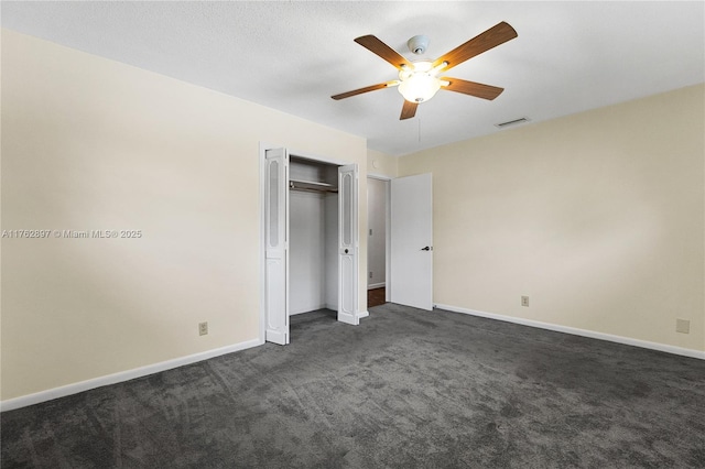 unfurnished bedroom with visible vents, baseboards, ceiling fan, dark carpet, and a closet