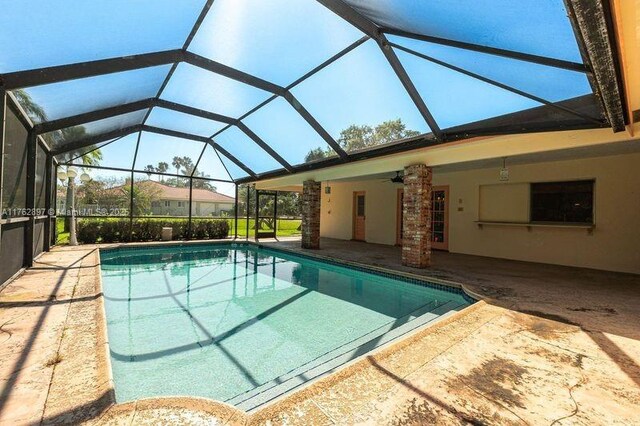 outdoor pool with a lanai, a patio area, and ceiling fan