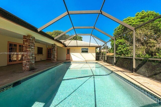 outdoor pool featuring french doors, a lanai, and a patio area