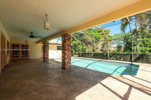 pool with glass enclosure, ceiling fan, french doors, and a patio area