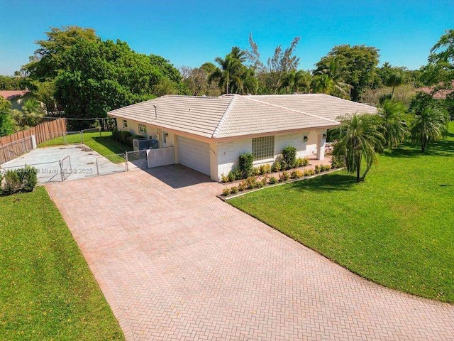 ranch-style house with a front yard, fence, an attached garage, a tiled roof, and decorative driveway