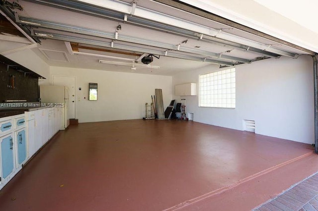 garage featuring a garage door opener and freestanding refrigerator