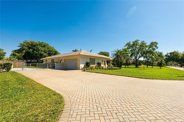 ranch-style house with a front lawn, decorative driveway, fence, and a garage