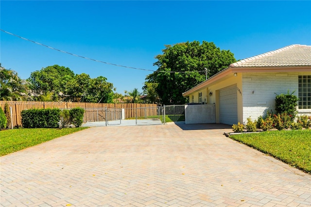 exterior space with a gate, decorative driveway, fence, and a garage