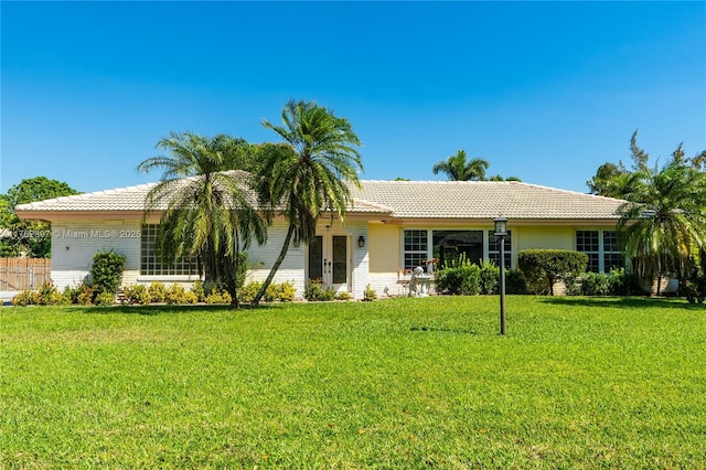 ranch-style home featuring a front lawn and a tile roof