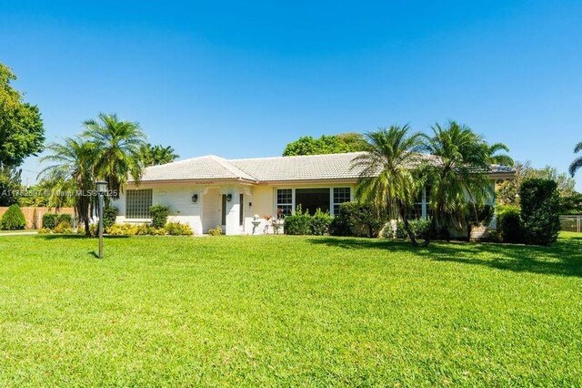 ranch-style home featuring a tiled roof and a front yard